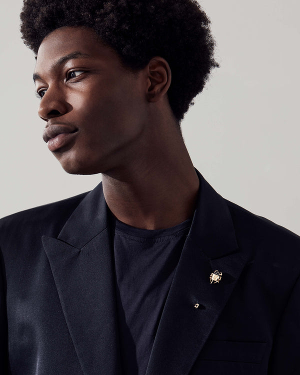 Suit jacket with Stephen Webster Jitterbug Toro Beetle lapel pin — yellow-gold beetle pin with black diamonds and spinel