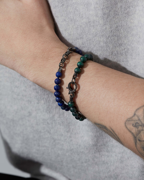Macro close-up of Stephen Webster Thorn Malachite Beaded Bracelet on model’s wrist showing polished malachite beads and black sapphire detail