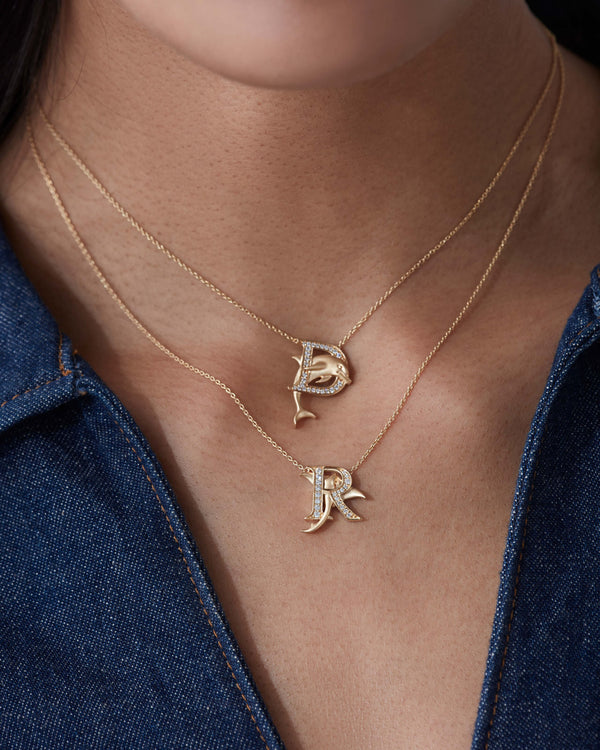 Model close up wearing Stephen Webster D is for Dolphin initial necklace in 18ct yellow gold with diamonds, personalised luxury gift for her
