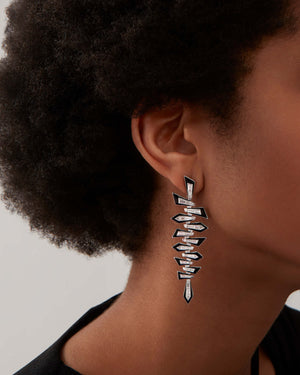 Model wearing Stephen Webster Enamel Shattered Long Drop Earrings in 18ct white gold with white diamonds and black enamel, glamorous luxury jewellery gift styling