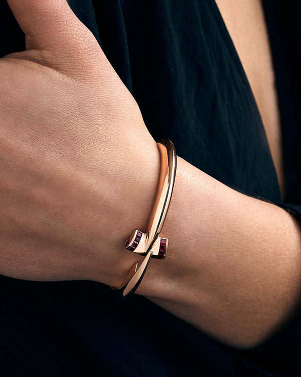 Model wearing Stephen Webster Hammerhead Bangle in 18ct rose gold with rubies, luxury jewellery styling on wrist
