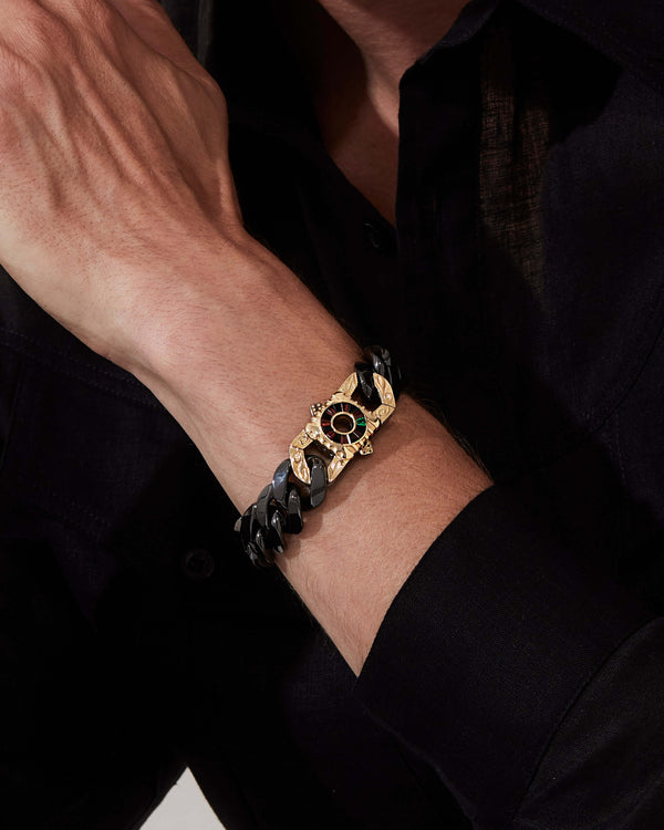 Model wearing Stephen Webster Rat Race clasp in 18k yellow gold & sterling silver with black onyx, red garnet, emerald and mother of pearl back plate