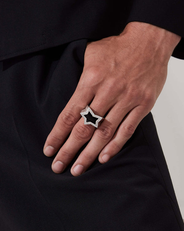 Close up of model wearing Stephen Webster Sex & Drugs & Rock & Roll cross-shaped ring in sterling silver with central black onyx star and pavé diamonds.