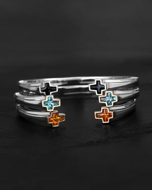 Flat-lay of Stephen Webster Sex & Drugs & Rock & Roll bangles — sterling silver cuff with cross ends