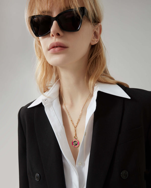 Model wearing Stephen Webster Bonus Track gold pendant necklace — showing pendant size, enamel detail and gold finish