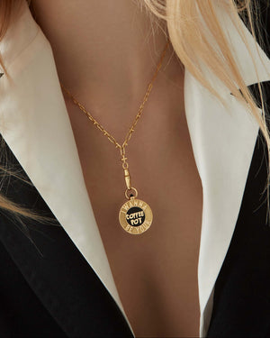 Close-up of the Stephen Webster Coffee Pot 18 ct gold pendant worn on model’s neck, showing black enamel vinyl design and engraved lettering