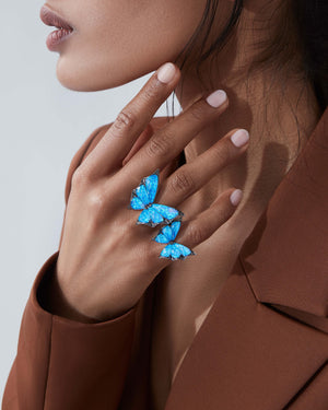 Close up of model wearing Stephen Webster Crystal Haze blue cocktail butterfly ring — 18 ct white gold statement ring