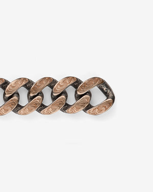 Close-up detail of Stephen Webster Cuban bracelet in silver & rose gold — engraved smoke-pattern links and polished metal texture visible
