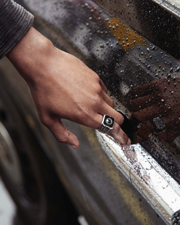 Close-up view of model’s hand wearing the black-sapphire Cuban Leaf ring — detailed view of gemstone, enamel finish, engraved band and proportions under light