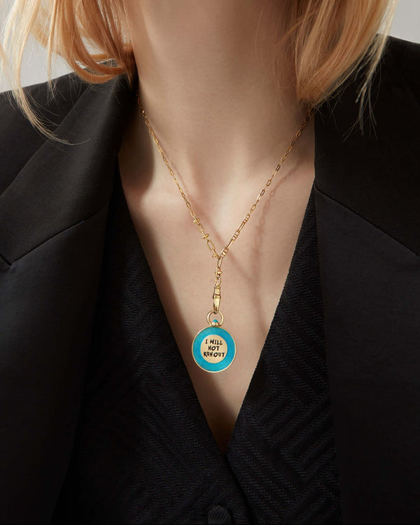 Close-up of the Stephen Webster Electric Meter 18 ct gold pendant worn on the model’s neck, showing pink enamel vinyl design and engraved lettering