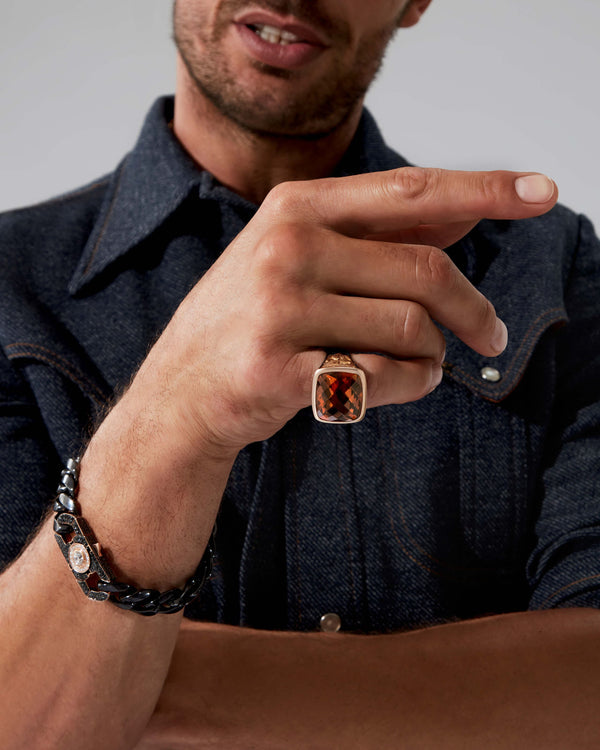 Close-up of finger wearing the Embankment Fish ring — cushion-cut cognac quartz, rose-gold panels and silver band detail visible under light