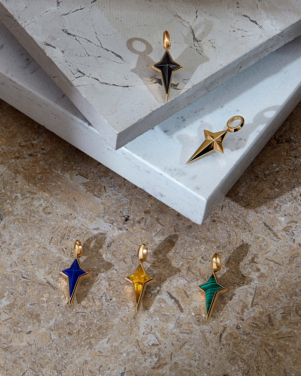 Close-up detail of Stephen Webster New Cross earring charm — lapis inlay and polished gold finish highlighted with other colours