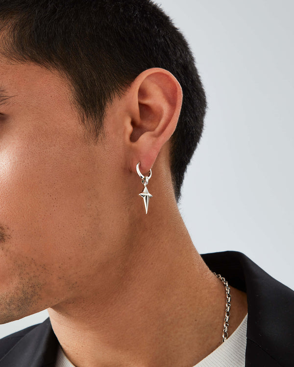 Close-up of model’s ear wearing Stephen Webster New Cross silver charm — highlighting polished finish and charm detail