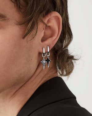 Close-up of model’s ear wearing Stephen Webster New Cross silver onyx charm — highlighting inlay, polished finish and setting