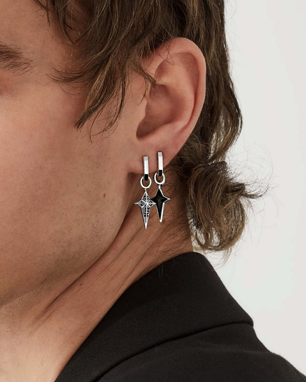 Close-up of model’s ear wearing Stephen Webster New Cross silver onyx charm — highlighting inlay, polished finish and setting