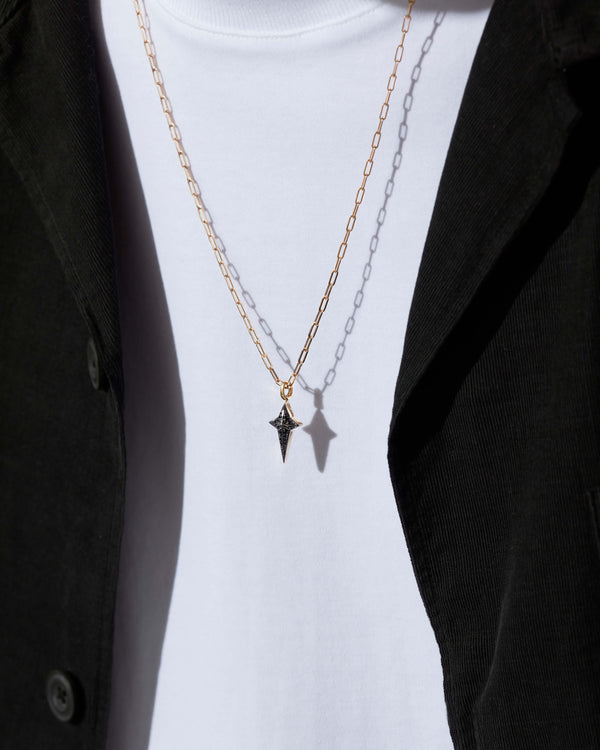 Model wearing Stephen Webster New Cross gold pendant with black diamonds — pendant centered on chest, highlighting size and sparkle