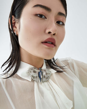 Model wearing Stephen Webster Flying Fish brooch pinned to blouse, showcasing scale and high-end jewellery styling