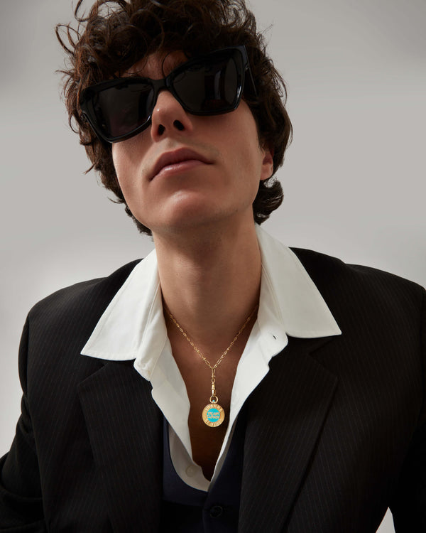 Male model wearing Stephen Webster Vacuum Cleaner gold pendant on chain — showing pendant size, enamel detail and gold finish