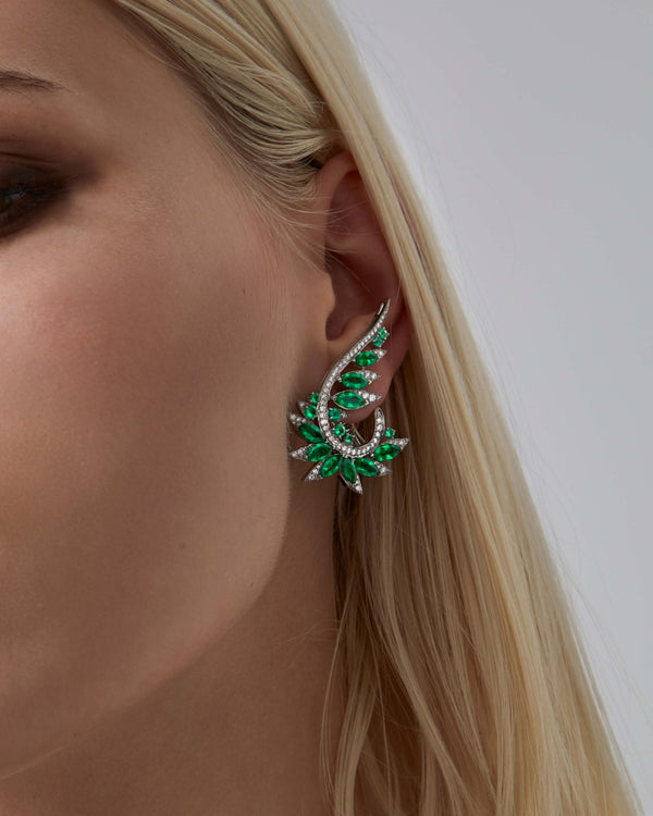 White Gold and Emerald Plumage Earrings worn on ear showcasing gemstone and diamond sparkle