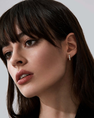 Yellow gold diamond baguette sleeper earrings worn on the ear